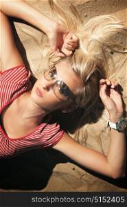 Pretty blond woman laying on the white, celan sand