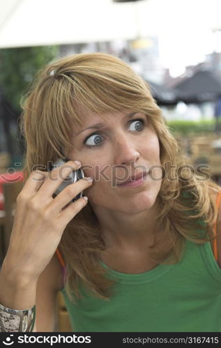 pretty blond woman looking shocked while listening to the phone