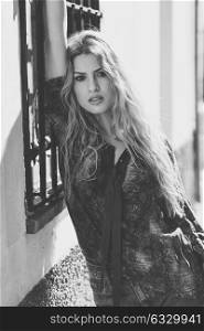 Pretty blond woman, model of fashion, in urban background. Beautiful girl wearing shirt and blue jeans. Black and white shoot
