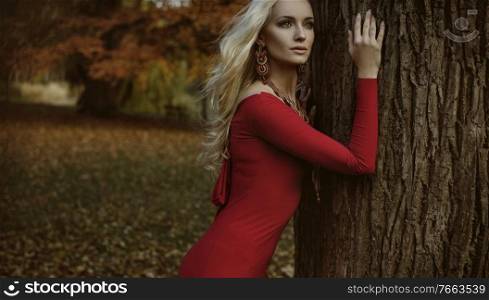 Pretty blond woman posing in an autumnal forest