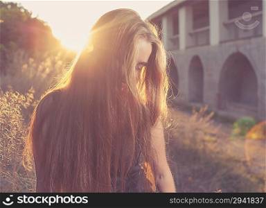 pretty blond women at autumn sunset. Her face hidden by sand-color hair. Backlit