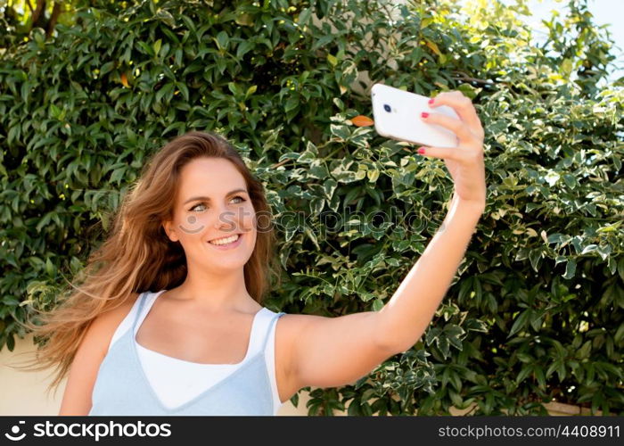 Pretty blonde girl in the park with a mobile