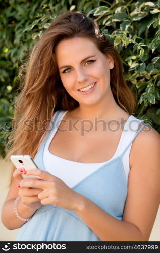 Pretty blonde girl in the park with a mobile