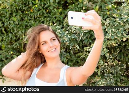 Pretty blonde girl in the park with a mobile