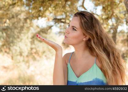 Pretty blonde girl throwing a kiss on a sunny day