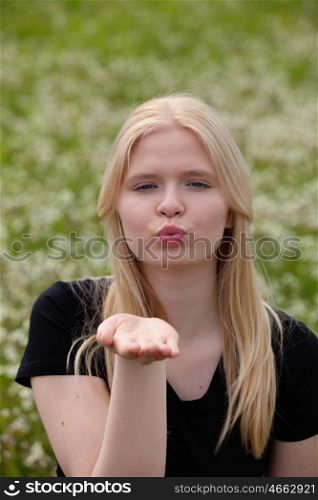 Pretty blonde girl throwing a kiss surrounded of many flowers