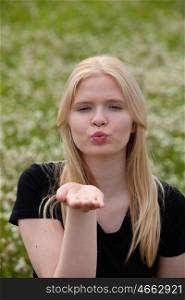 Pretty blonde girl throwing a kiss surrounded of many flowers