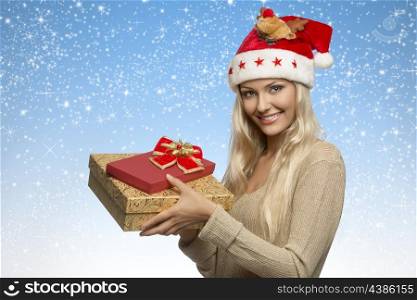 pretty blonde girl with christmas hat and golden dress taking gift boxes in the hands and smiling