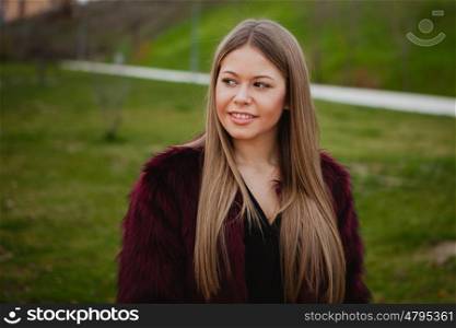 Pretty blonde girl with fur coat in the park at winter