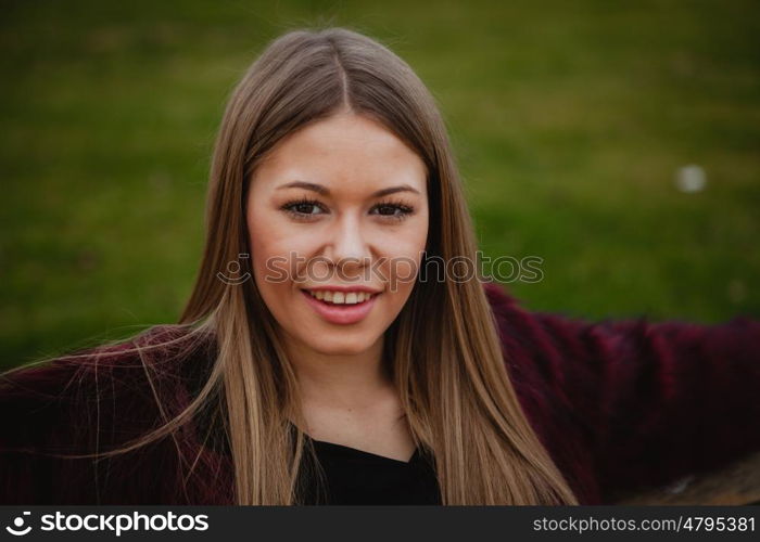 Pretty blonde girl with fur coat in the park at winter