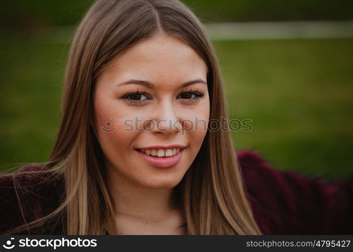 Pretty blonde girl with fur coat in the park at winter