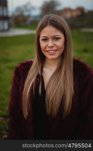 Pretty blonde girl with fur coat in the park at winter