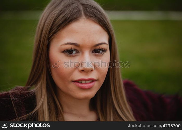 Pretty blonde girl with fur coat in the park at winter