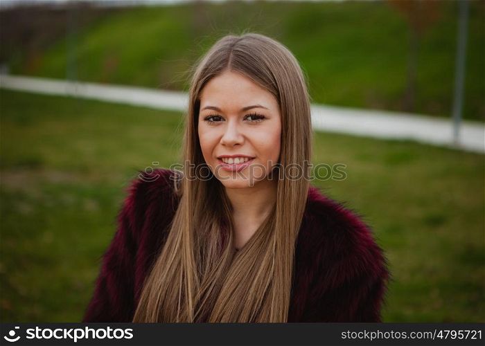 Pretty blonde girl with fur coat in the park at winter