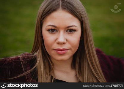 Pretty blonde girl with fur coat in the park at winter