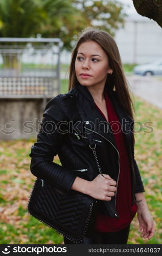 Pretty blonde girl with leather jacket in the street in a autumn day