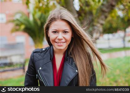 Pretty blonde girl with leather jacket in the street in a autumn day