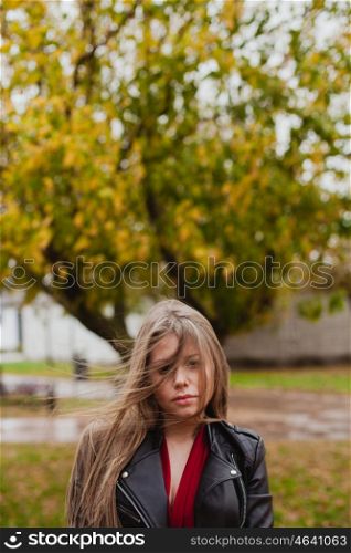 Pretty blonde girl with leather jacket in the street in a autumn day