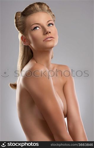 pretty blonde girl with naked torso and creative hair style, she is turned of three quarters at left and looks up