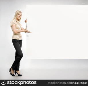 Pretty blonde secretary showing an empty board,lots of copyspace