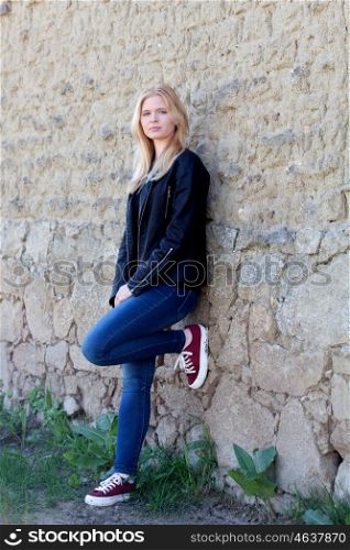 Pretty blonde single woman portrait outdoors with a wall of background