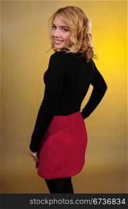 Pretty blonde teenager in a black sweater and a pink skirt