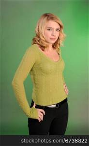Pretty blonde teenager in a green knit sweater and black slacks