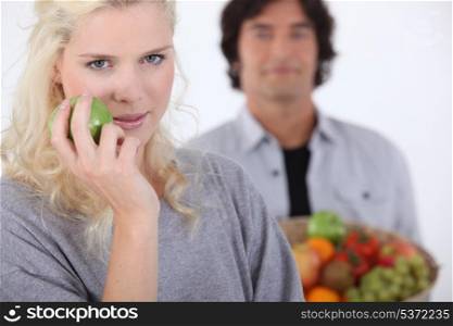 pretty blonde with apple and man holding basket in background