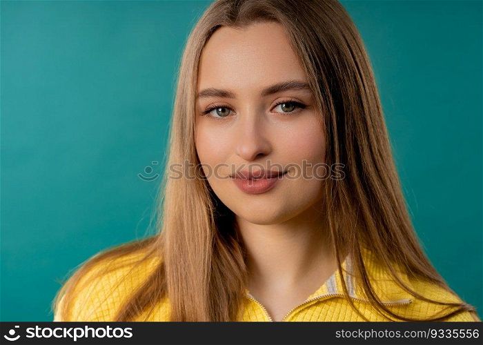 Pretty blonde woman, big lips on teal background. Smiling natural healthy girl lady with european appearance looking at camera. High quality photo. Pretty blonde woman, big lips on blue background. Smiling natural healthy girl
