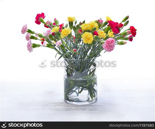 pretty bouquet of colorful flowers - carnation- in a glass jar on white background