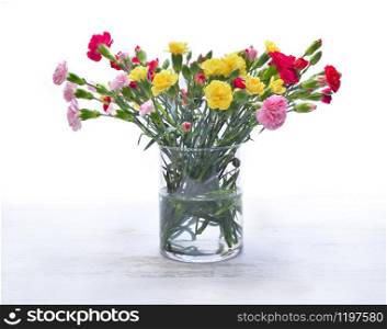 pretty bouquet of colorful flowers - carnation- in a glass jar on white background