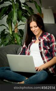 Pretty brunette girl at home with a laptop.