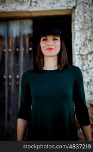 Pretty brunette girl in black with a stylish hat and a old wooden door of background