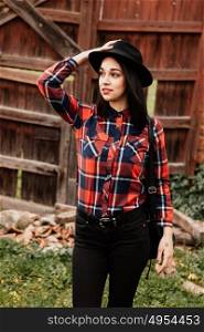 Pretty brunette girl with red plaid shirt and black hat