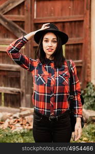 Pretty brunette girl with red plaid shirt and black hat