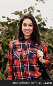 Pretty brunette girl with red plaid shirt in the field