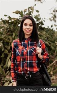 Pretty brunette girl with red plaid shirt in the field