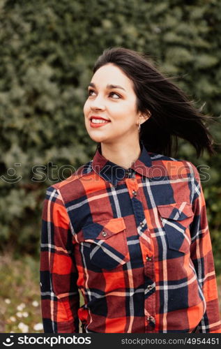 Pretty brunette girl with red plaid shirt in the park