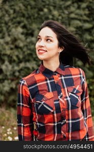 Pretty brunette girl with red plaid shirt in the park