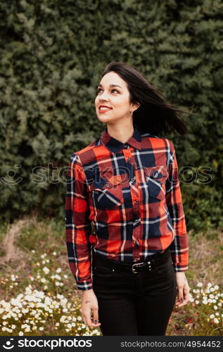 Pretty brunette girl with red plaid shirt in the park