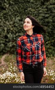 Pretty brunette girl with red plaid shirt in the park
