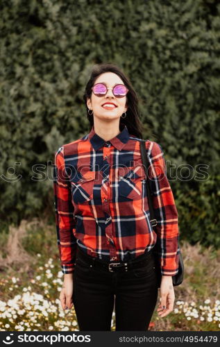 Pretty brunette girl with red plaid shirt in the park