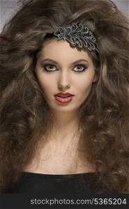 pretty brunette girl with voluminous brown curly hair-style and sexy make-up posing in close-up portrait. Glitter accessory in the hair