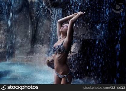 Pretty brunette relaxing next to a tropical waterfall