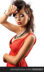 pretty brunette with fashion hair style, red dress and some necklaces. Her body is turned in profile, she looks down and her right hand is on her front