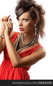 pretty brunette with fashion hair style, red dress and some necklaces, she is turned of three quarters at right, her hands are joined near the face and she looks in front of her