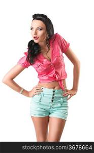 pretty brunette with green shorts and pink shirt, she is in front of the camera with both hands on her hips, she looks at right