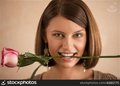 Pretty brunette woman holding rose in her mouth