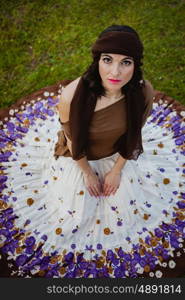 Pretty brunette woman sitting on the floor with a flowered skirt. View from above