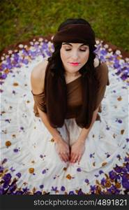 Pretty brunette woman sitting on the floor with a flowered skirt. View from above